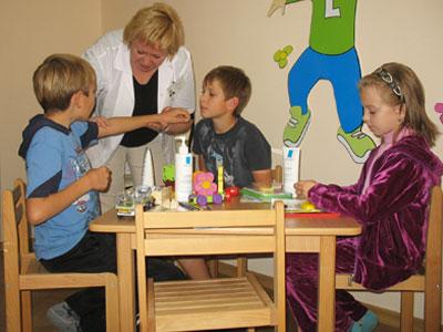 Профессор Татьяна Проценко показывает Никите Чурсину и другим детям, как правильно наносить бальзам на кожу руки. 